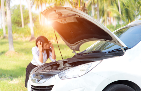 Sad business women with a broken car with open hoodの写真素材