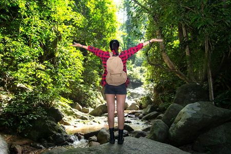 Traveler woman feeling victorious facing on the water fall.の写真素材