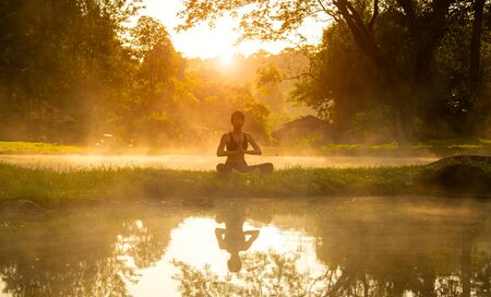 Healthy woman lifestyle exercising vital meditate and energy yoga in morning the spring nature background. Healthy Concept.の写真素材