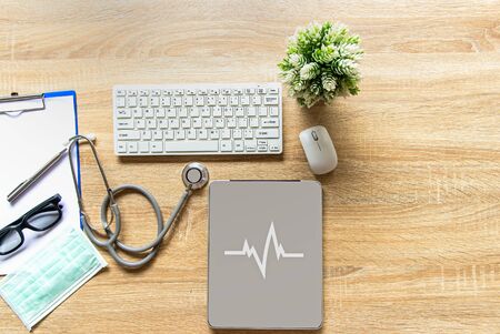 The doctor with a medical stethoscope check heart near a laptop on a wooden table.  Healthy Conceptの写真素材