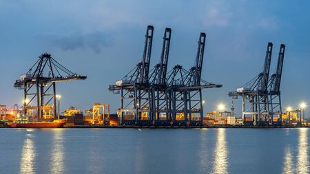 Container Cargo freight ship with working crane bridge in shipyard at dusk for Logistic Import Export background.  Industry Conceptの写真素材