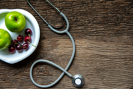 Diet and weight loss for healthy care with medical stethoscope, fitness equipment,measuring tap,fresh water and green apple on wooden background top view.  Healthy Concept.の写真素材
