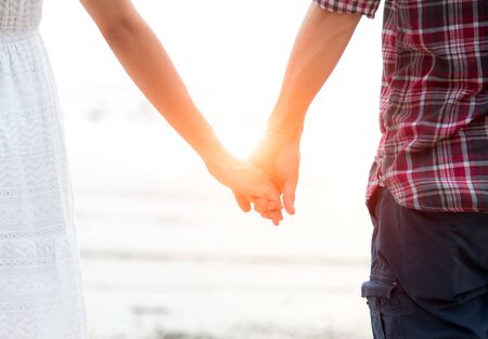 Young couple in love, Attractive man and woman enjoying romantic evening on the beach, Holding hands watching the sunsetの写真素材