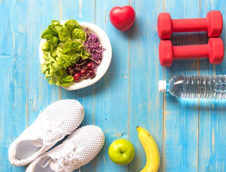 Healthy lifestyle sport equipment fitness, sneakers, green apple, fresh water and healthy food on blue wood background.  Healthy Concept.の写真素材