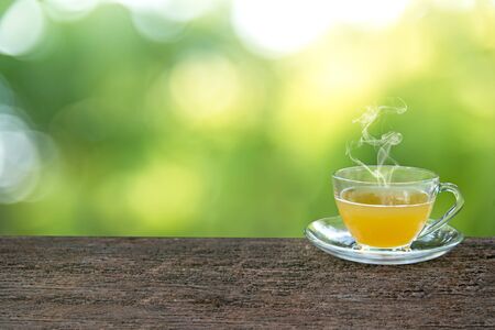 Tea cup with and tea leaf sacking on the wooden table and green backgroundの写真素材