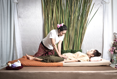 Thai Masseuse doing massage for woman in spa salon. Asian beautiful woman getting thai herbal massage compress massage in spa.She is very relaxed.  Healthy Conceptの写真素材