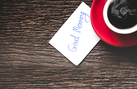 A red cup of coffee with write good morning on old wooden table. Lifestyle Conceptの写真素材