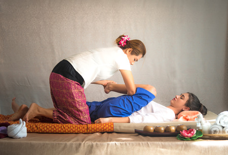 Thai Masseuse doing massage for woman in spa salon. Asian beautiful woman getting thai herbal massage compress massage in spa.She is very relaxed.  Healthy Conceptの写真素材