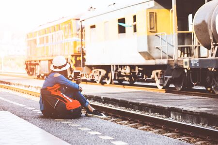 Traveler and tourist women wearing backpack holding map and drinking coffee, waiting for a train, vintage tone. Travel Concept.の写真素材