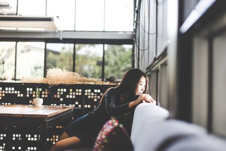 Beautiful cute asia girl in the cafe near the window with coffee smiling and relax, vintage tone.  Lifestyle Conceptの写真素材