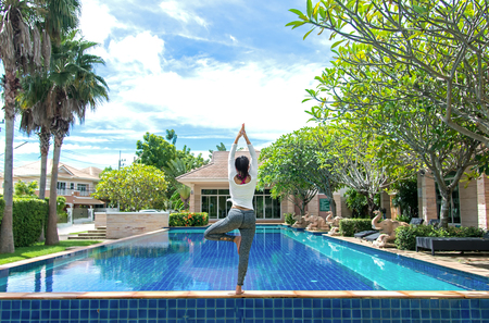 Asia woman doing yoga fitness exercise for relax and healthy beside swimming pool background.  Healthy Concept.の写真素材