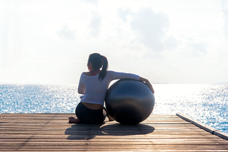 Healthy woman lifestyle balanced yoga ball practicing meditate and energy on the bridge in morning the seashore. Healthy Concept.の写真素材