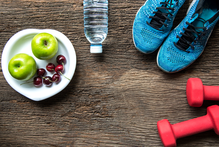 Healthy lifestyle sport equipment fitness, sneakers, green apple, fresh water and healthy food on old wood background.  Healthy Concept.の写真素材