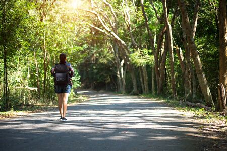 Travel asia woman standing on forest trail and looking away. Female with backpack on hike in nature. Travel Conceptの写真素材