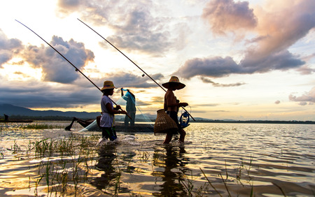 Asian boy and girl playing in the river with fisherman, in the morning sunrise, Thailand.のeditorial素材