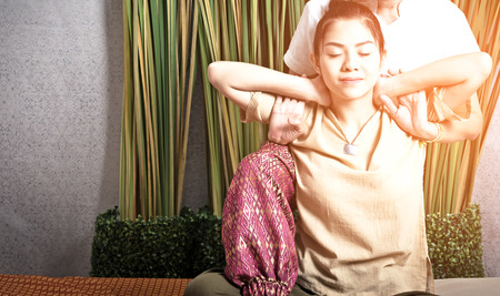 Thai Masseuse doing massage for woman in spa salon. Asian beautiful woman getting thai herbal massage compress massage in spa.She is very relaxed.  Healthy Conceptの写真素材