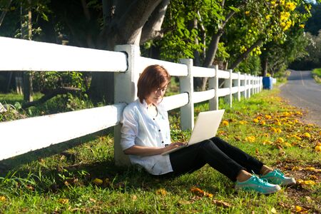Young women lying in summer grass playing laptop and relax, sunny day, greenery 2017の写真素材