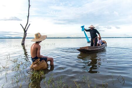 Asian boy and girl playing in the river with fisherman, in the morning sunrise, Thailandのeditorial素材