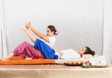 Thai Masseuse doing massage for woman in spa salon. Asian beautiful woman getting thai herbal massage compress massage in spa.She is very relaxed.  Healthy Conceptの写真素材