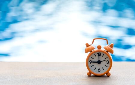 Retro alarm clock on table near swimming poolの写真素材