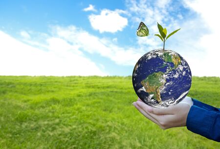 Green world with butterfly and leave in man hand, green background, Earth image provided by Nasa.の写真素材