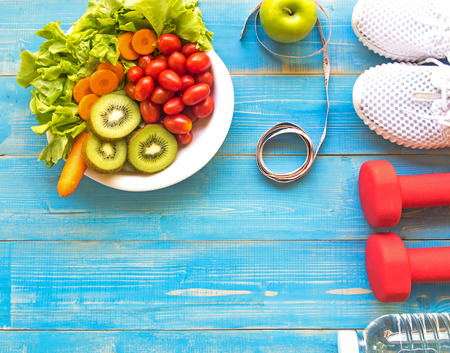 Healthy lifestyle for women diet with sport equipment, sneakers, measuring tape, vegetable fresh, green apples and bottle of water on blue wooden.  Healthy Concept.の写真素材