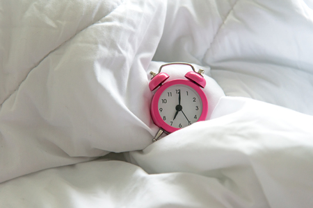 Pink Alarm clock get up six oclock on bed in morning with sun light.  Lifestyle Conceptの写真素材