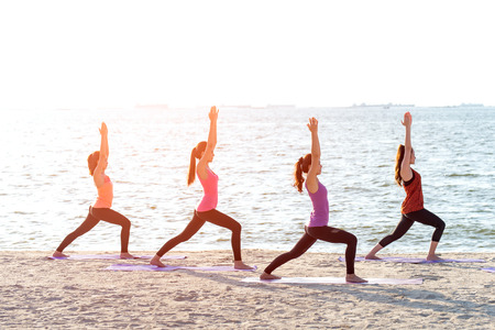 Asia people group making warrior pose on beach, fitness, sport, yoga and healthy lifestyle.  Healthy Conceptの写真素材