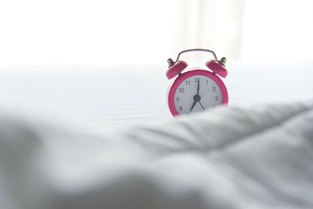 Pink Alarm clock on bed in morning with sun light