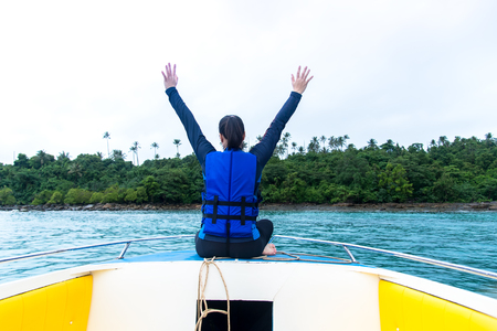 Back view of the young woman in hat relaxing on the boat and looking at the island.  Travel Conceptの写真素材