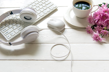Headphones and coffee cup on wooden desk table with pink flower. Music  and lifestyle concept. Top view with copy spaceの写真素材