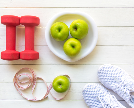 Diet and weight loss for healthy care with  fitness equipment,fresh water and fruit healthy,apple green apple, on white wooden background top view.  Healthy and Diet Concept.の写真素材