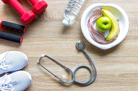 Healthy lifestyle for women diet with sport equipment, sneakers, measuring tape, fruit healthy green apples and bottle of water on wooden.  Healthy Concept.の写真素材