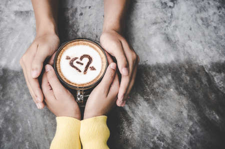 Top view with copy space.  Couple in love holding hands with coffee love on  table, vintage tone. Lifestyle Conceptの写真素材
