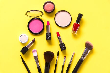 Cosmetics and fashion background with make up artist objects: lipstick, eye shadows, mascara ,eyeliner, concealer, nail polish, yellow colorful background.  Lifestyle Conceptの写真素材