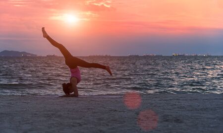 Silhouette young woman lifestyle exercising vital meditate and practicing yoga on the beach at sunset.  Healthy Concept.の写真素材