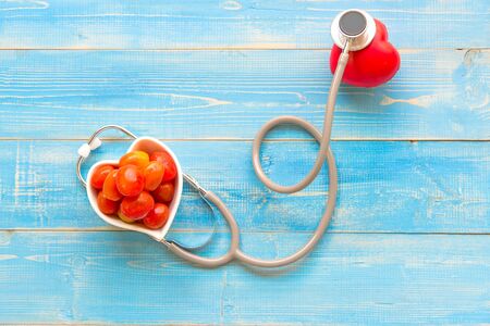 One single alone red heart love shape hand exercise ball with bandage MD medical doctor physician's stethoscope blue wood background.  Healthy Conceptの写真素材