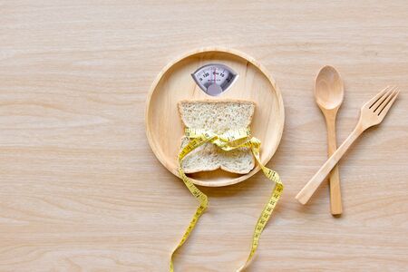 Weight scale with wholesome slice of bread and measuring tape on the wood plate for slimming weight.  Diet and Healthy Conceptの写真素材