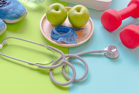 Diet slimming weight with green apple and measuring tap, scale weight, dumbbells, colourful background.  Diet and Healthy Conceptの写真素材