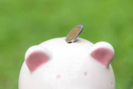 Holding piggy and putting a coin into piggy bank for future life.  Investment and Saving Concept. soft and select focusの写真素材