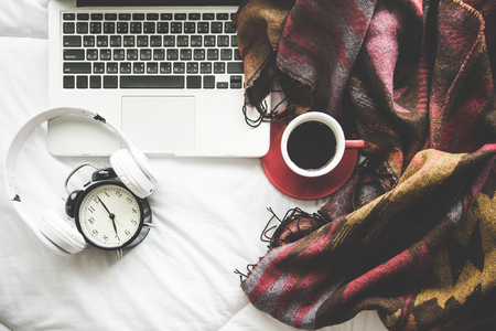 Cozy winter home background, cup of hot coffee with marshmallow, warm knitted sweater on white bed background, vintage tone.  Lifestyle conceptの写真素材