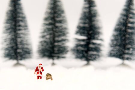 Miniature Santa Claus and artificial Christmas trees with snow background.  Holiday Conceptの写真素材