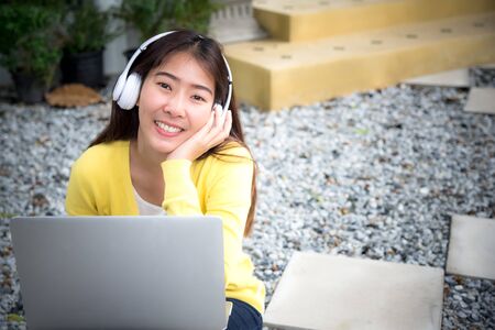 Lifestyle Girl enjoy listening music and play laptop in the nature park. Music and Lifestyle Concept.の写真素材