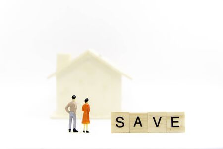Miniature couple for house representing home ownership and saving money the Real Estate business. Words of saving money concepts collected in crossword with wooden cubes. . Investment Concept.の写真素材