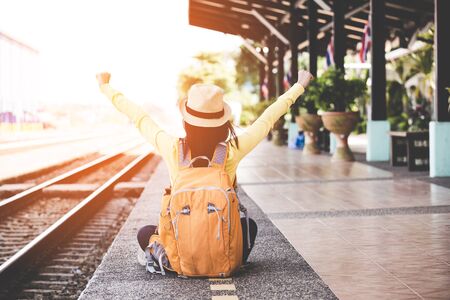Tourist asian lifestyle women wearing backpack holding map, traveler siting for waiting a train, so happy and relax for summer day, Travel Concept.の写真素材