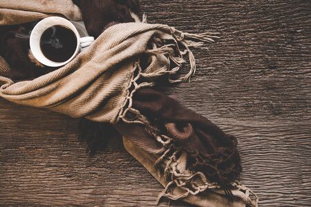 Cozy winter background, cup of hot coffee with marshmallow, warm knitted sweater on old wooden background, vintage tone.  Lifestyle conceptの写真素材