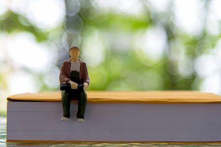 Miniature people sitting on book for the education, green nature background.  Education Conceptの写真素材