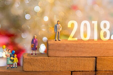 Miniature group happy family holding balloons standing on wooden 2018 with party happy new year, party background.の写真素材