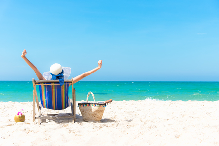 Summer Vacation. Beautiful young asian woman relaxing and happy on beach chair with cocktail coconut juice in holiday summer, blue sky background.  Travel and lifestyle Conceptの写真素材