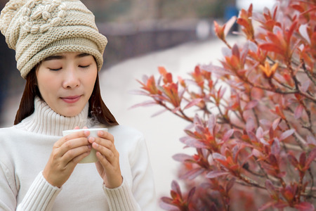 Winter and Autumn Season.  Woman's hand holding a white cup of hot coffee in cozy day, relax and happy in holiday.  Lifestyle Concept.の写真素材